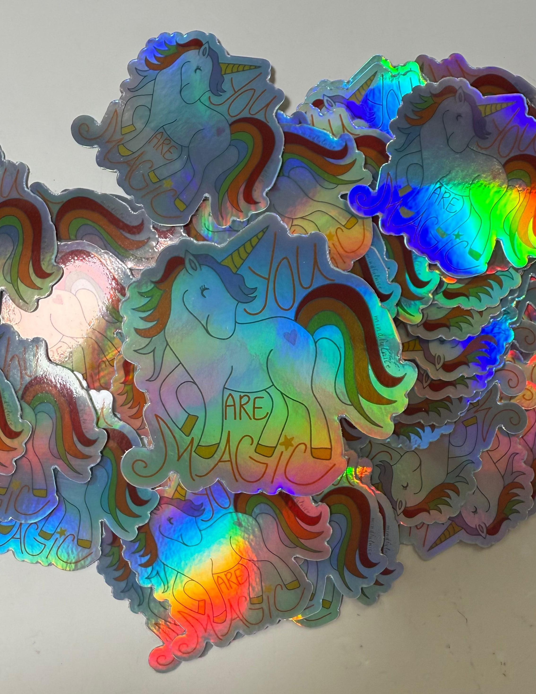 A holographic unicorn sticker with a rainbow effect and the phrase 'You Are Magic' written on it.